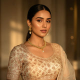 Model wearing gold plated classic polki leaf fringe choker necklace with flower pendant pearl drop and matching earrings on ivory lehenga