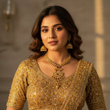 South Asian woman wearing antique gold plated pendant necklace set with jhumka earrings on gold lehenga - ruby pink variant