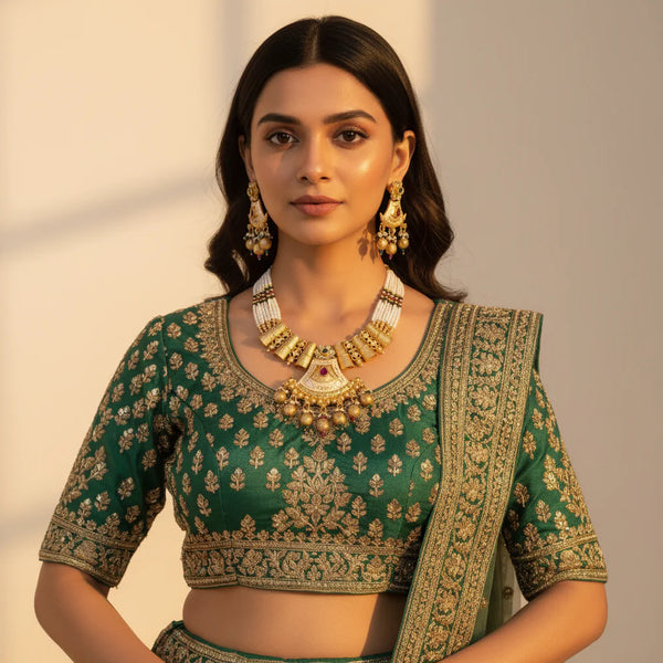 South Asian woman wearing antique gold meenakari pearl necklace set with earrings on green lehenga