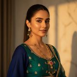 South Asian model wearing Kashmiri ruby polki long pendant necklace set with matching earrings in teal navy wedding outfit