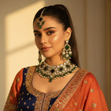 South Asian model wearing emerald green kundan polki choker set with earrings and tikka in navy orange wedding lehenga