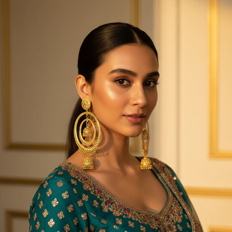 South Asian woman wearing gold plated oversized hoop jhumka earrings with double bell drop on teal outfit