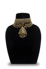 Gold plated floral rosette choker necklace close up with ghungroo chain swag and teardrop pendant on black velvet bust