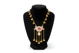 Kashmiri ruby polki long pendant necklace close up showing scrollwork frame ruby cabochon polki drop and gold chain tassels