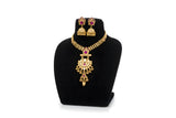 Antique gold pendant necklace set with jhumka earrings - ruby pink stone variant on black display stand