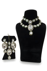 All white polki kundan wedding choker necklace set with long earrings and tikka on black display stand