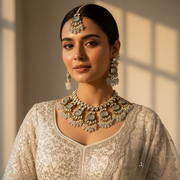 Model wearing mint green polki kundan emerald cut choker set with chandelier earrings and tikka on ivory bridal outfit