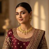 South Asian woman wearing gold plated filigree flower choker necklace set with earrings on maroon lehenga