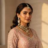 South Asian woman wearing all white polki kundan wedding choker set with long earrings and tikka on pink outfit