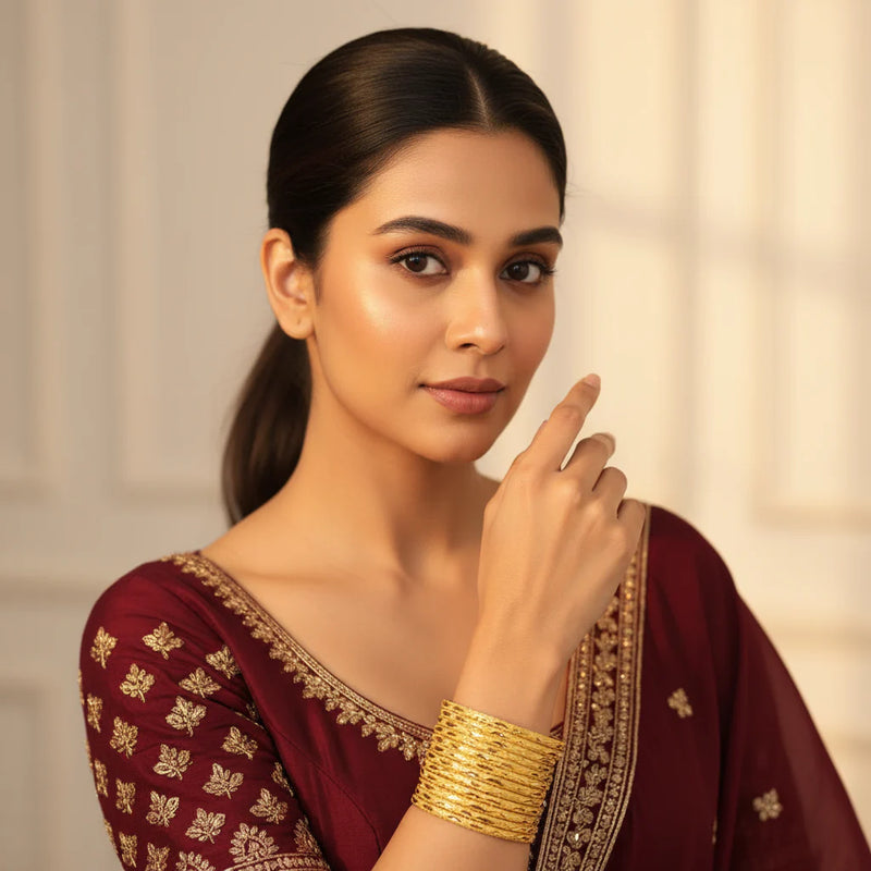 Model wearing gold plated cutwork lattice bangles set of 8 stacked on wrist with maroon embroidered suit