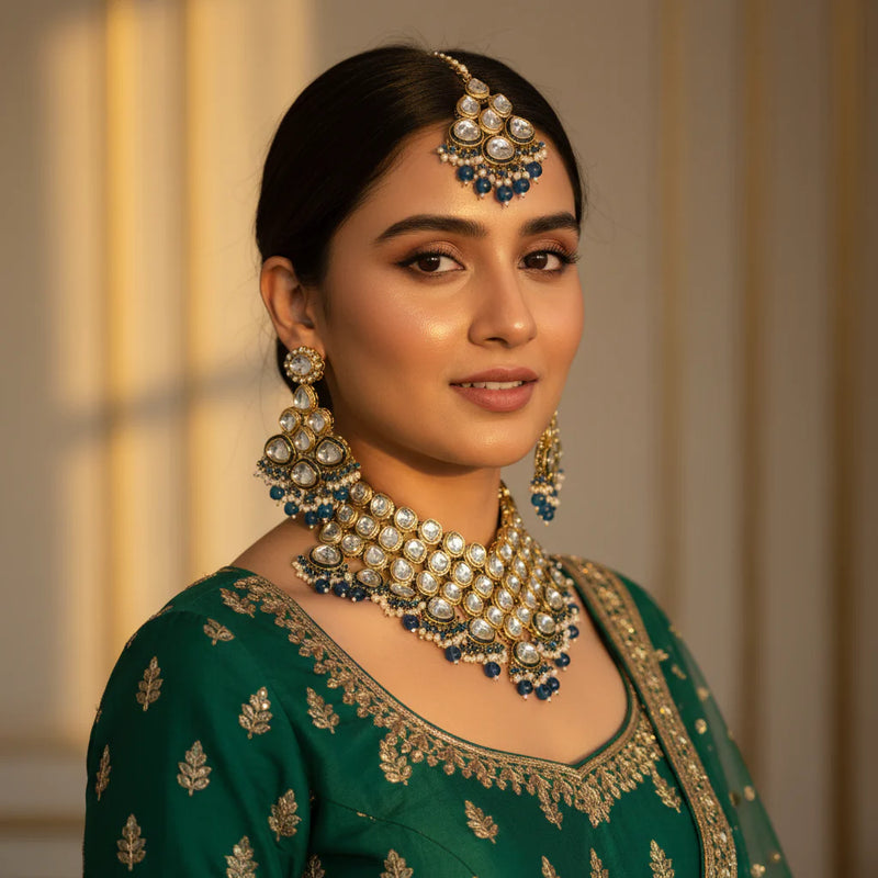 Model wearing gold polki kundan wedding choker set with blue crystal drops earrings and tikka on green lehenga