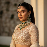 Model wearing emerald green kundan geometric choker set with earrings and tikka on ivory lehenga wedding