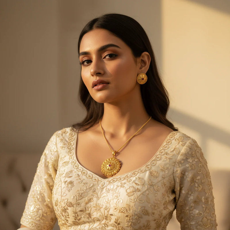 South Asian woman wearing gold plated filigree medallion pendant necklace set with stud earrings on ivory outfit