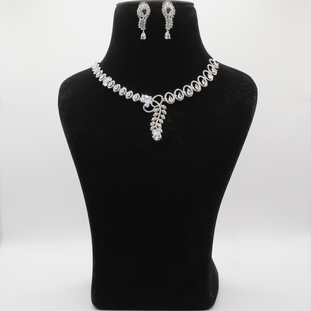 Jewelry set including a necklace and earrings on a black mannequin bust against a white background.