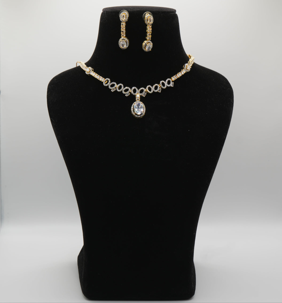 Jewelry set with necklace and earrings on a black mannequin bust against a white background