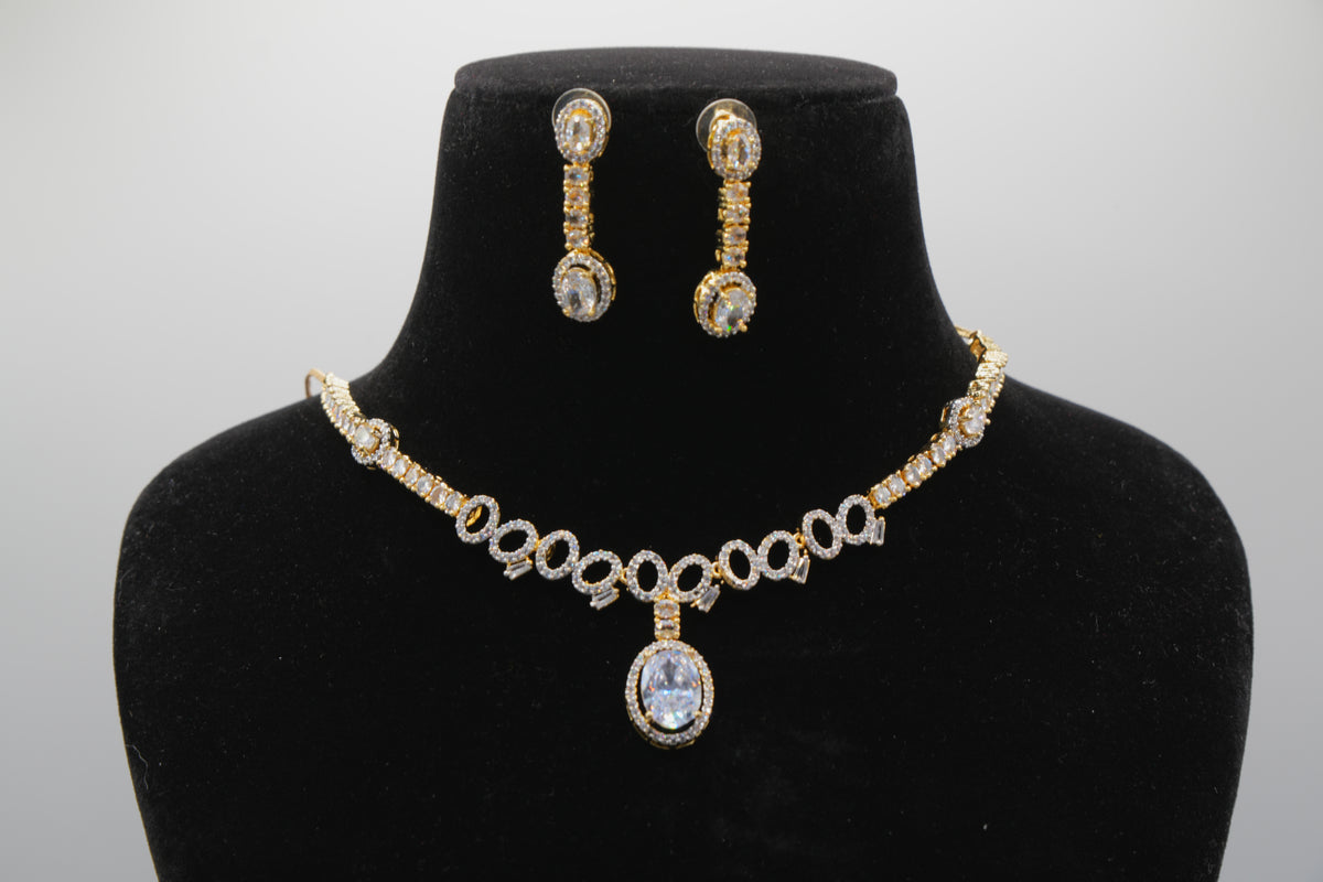 Gold necklace and earrings set on a black bust against a white background