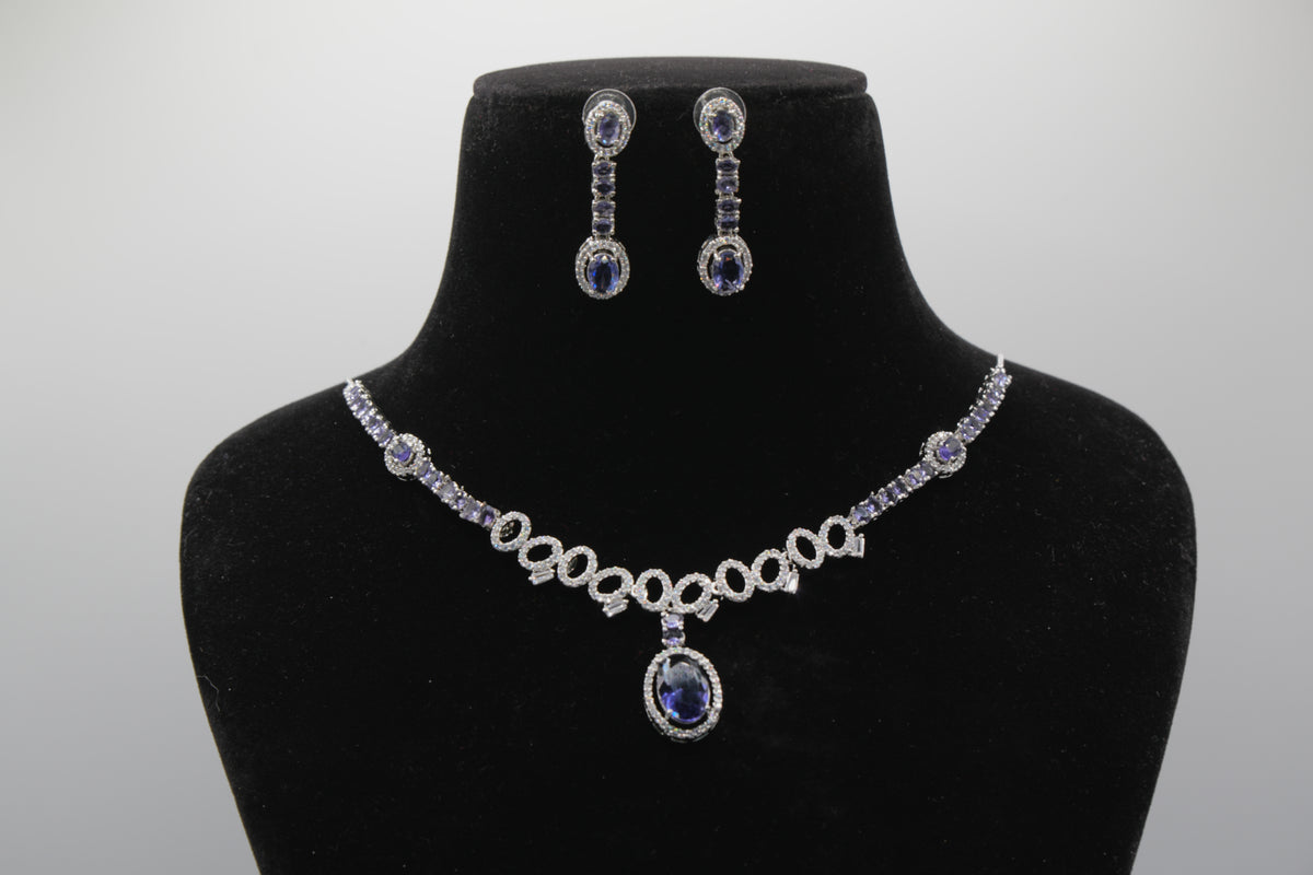 Blue Jewelry set with necklace and earrings on a black mannequin bust close up against a gray background