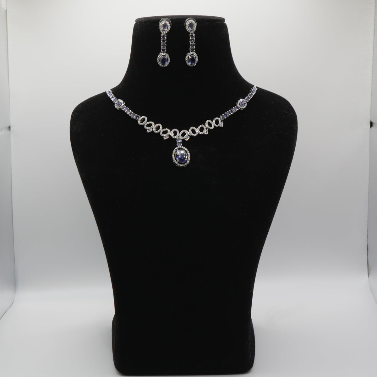 Blue Jewelry set including necklace and earrings on a black mannequin bust against a white background