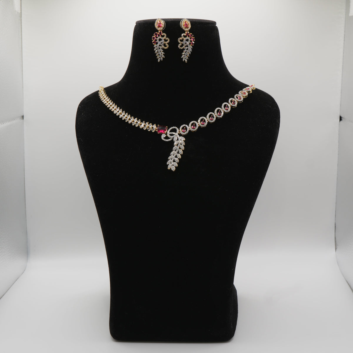 Ruby Red Jewelry set including a necklace and earrings on a black mannequin bust against a white background.