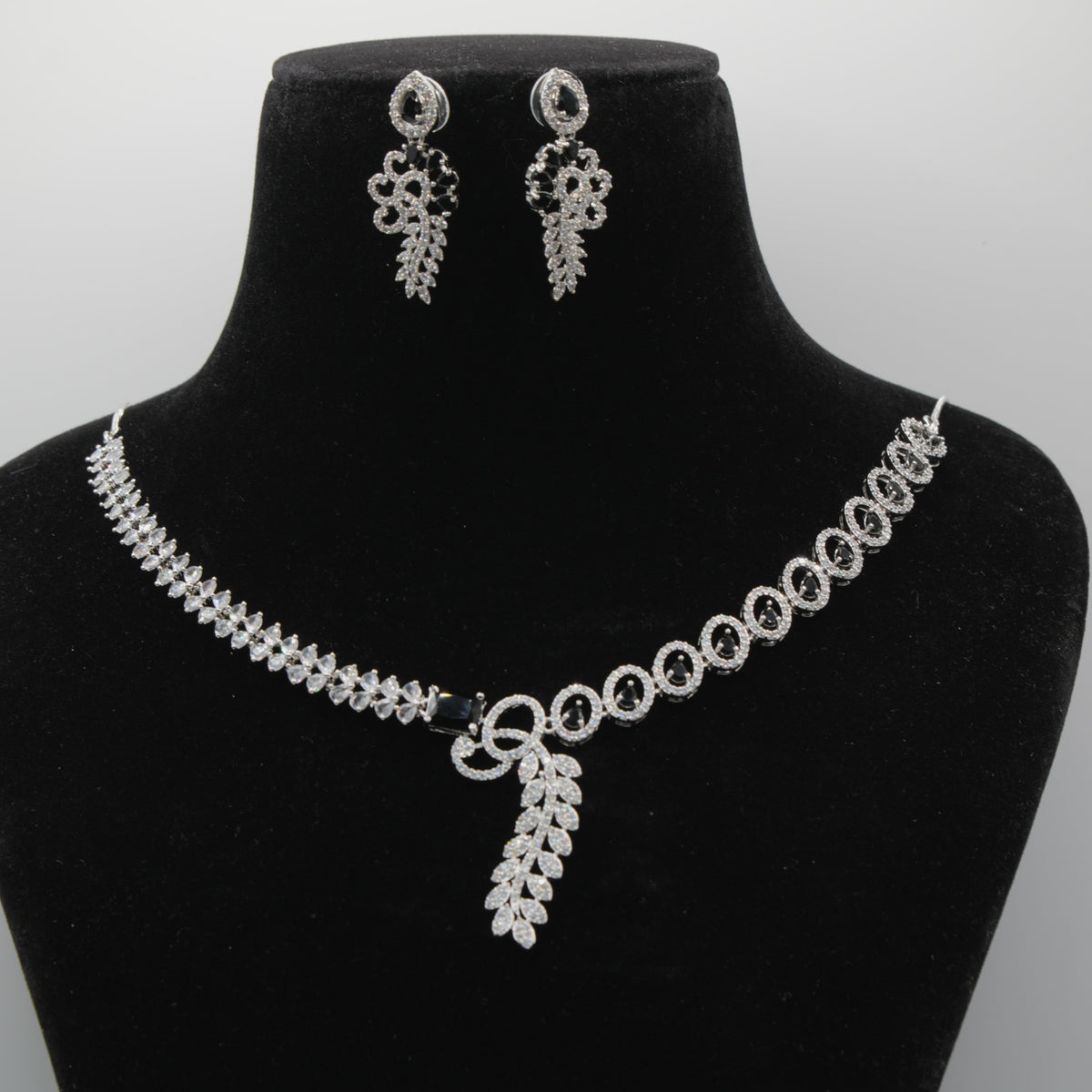 Black VVS necklace and earrings set on a black mannequin bust with a gray background