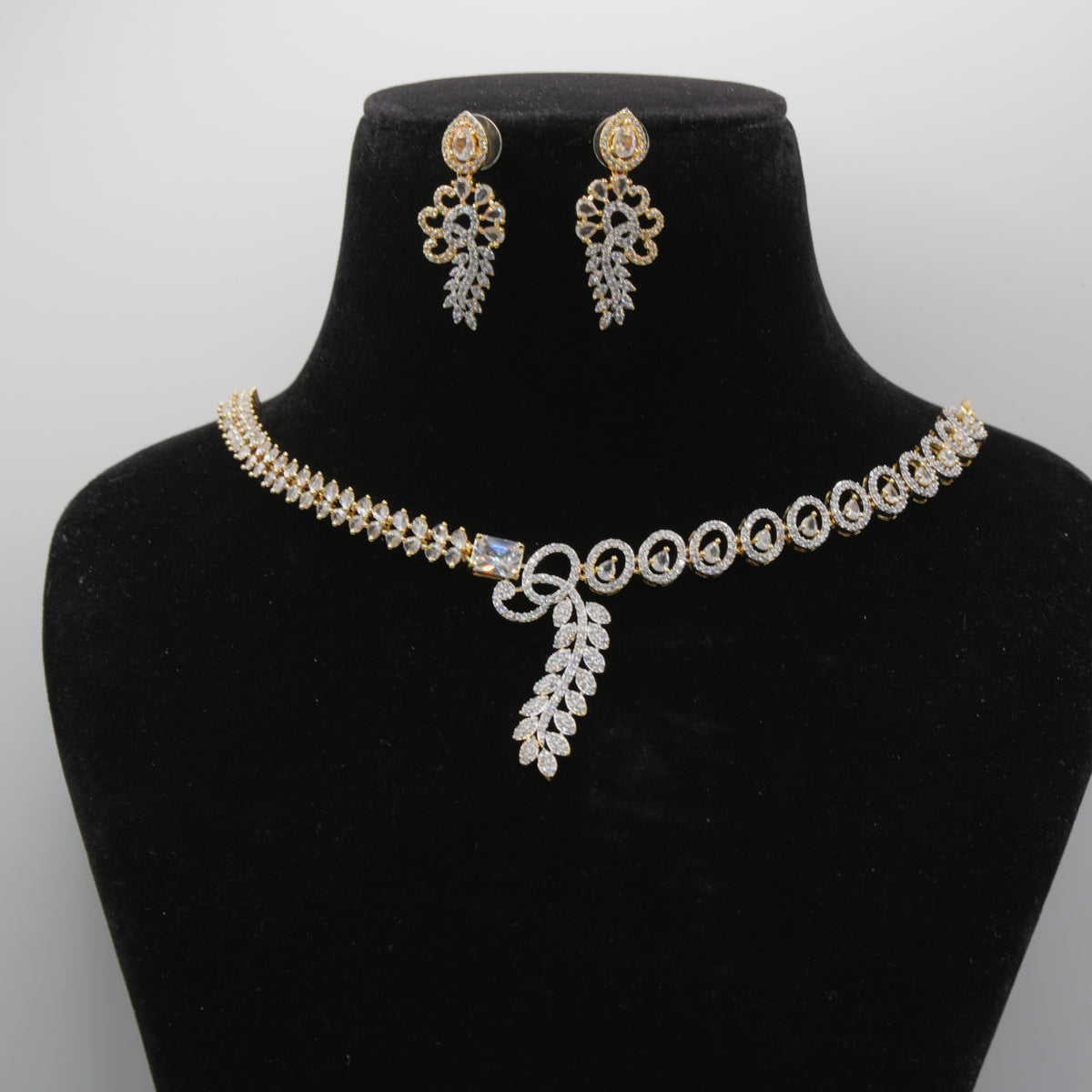 Jewelry set close up with necklace and earrings on a black mannequin bust against a gray background