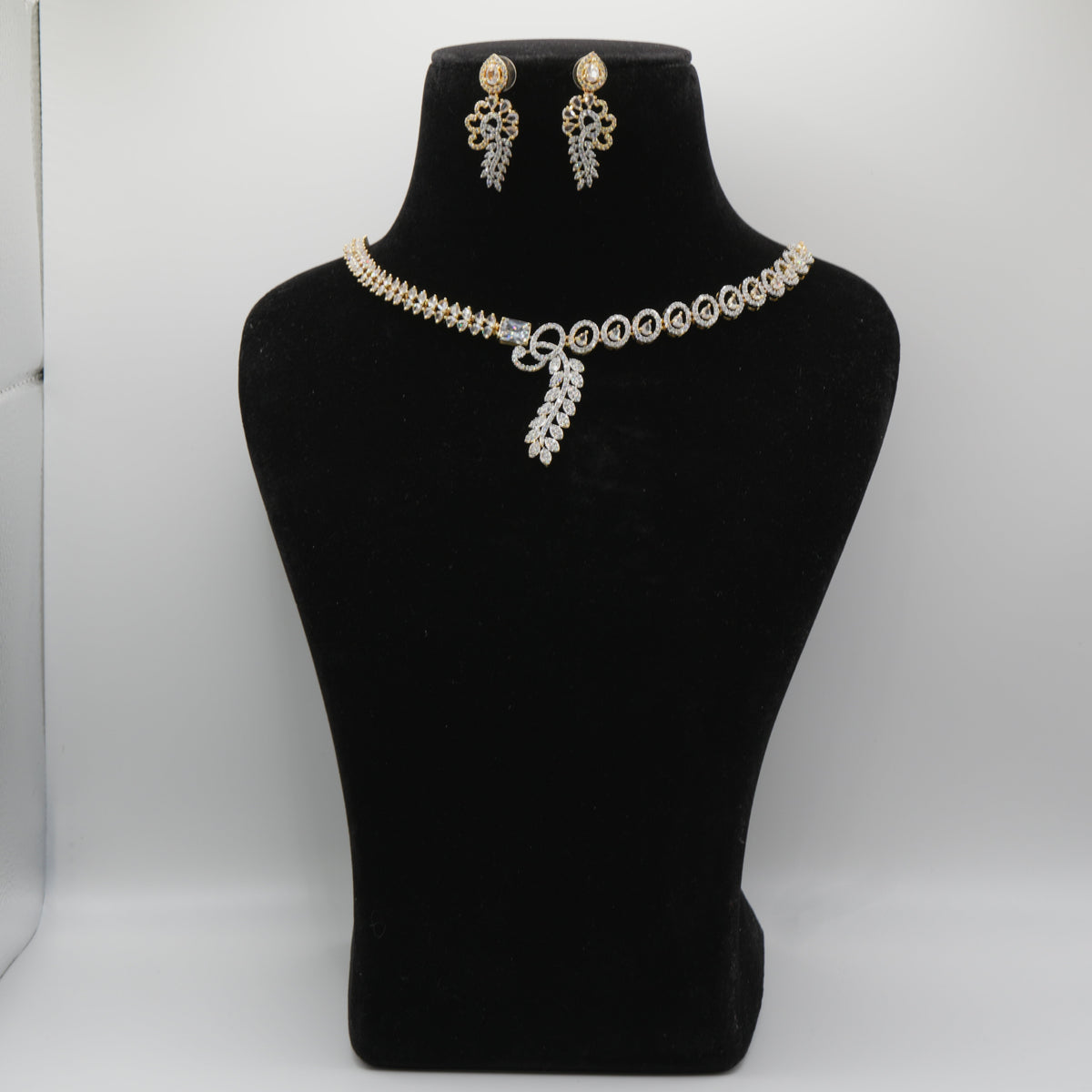 Pearl necklace and earrings set on a black mannequin bust against a white background