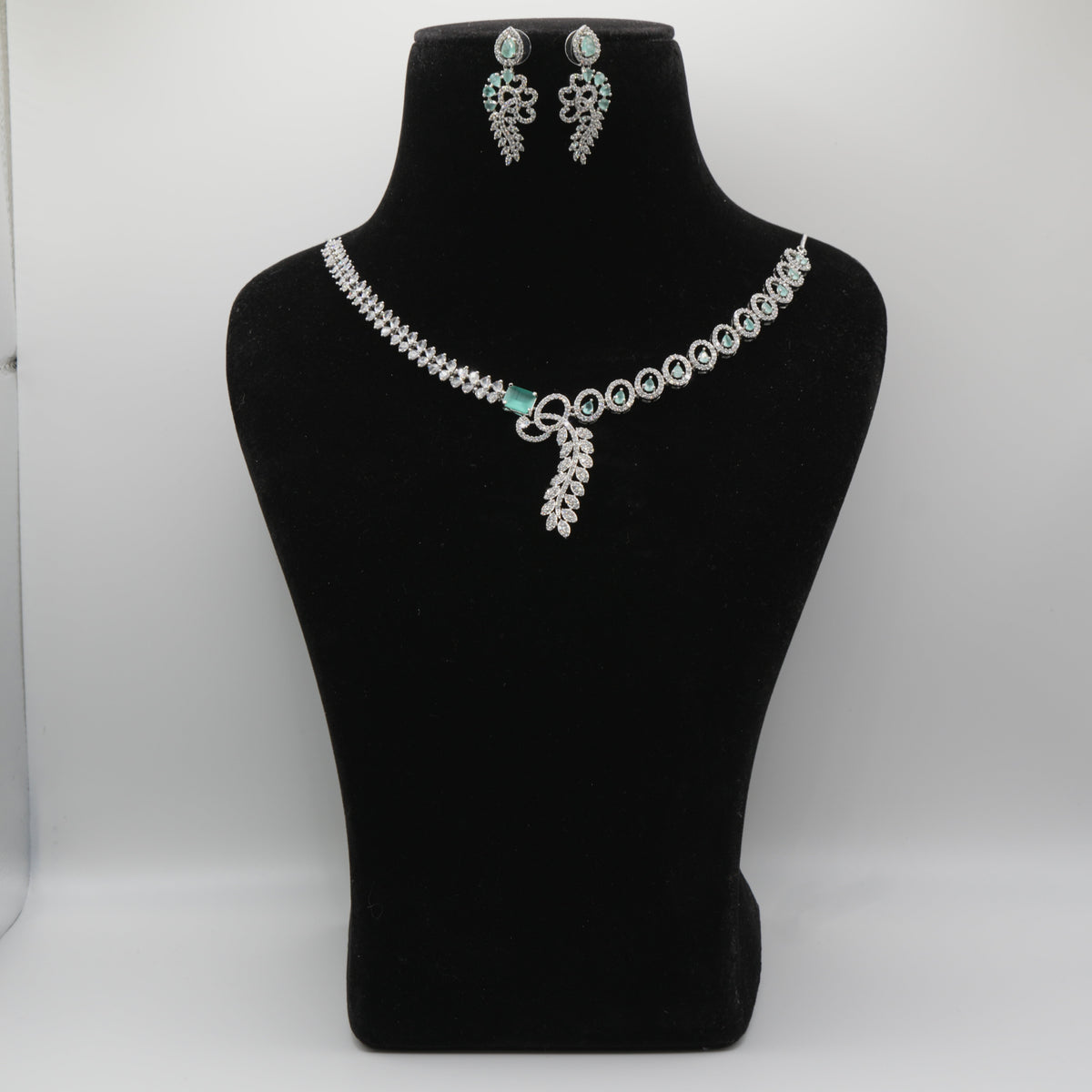 Mint diamond necklace and earrings on a black velvet bust with a gray background