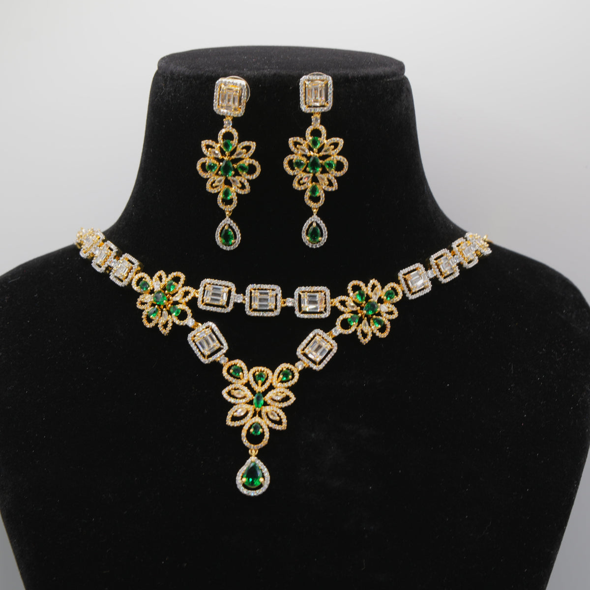 Close up of Emerald Green Jewelry set with necklace and earrings on a black mannequin bust against a white background