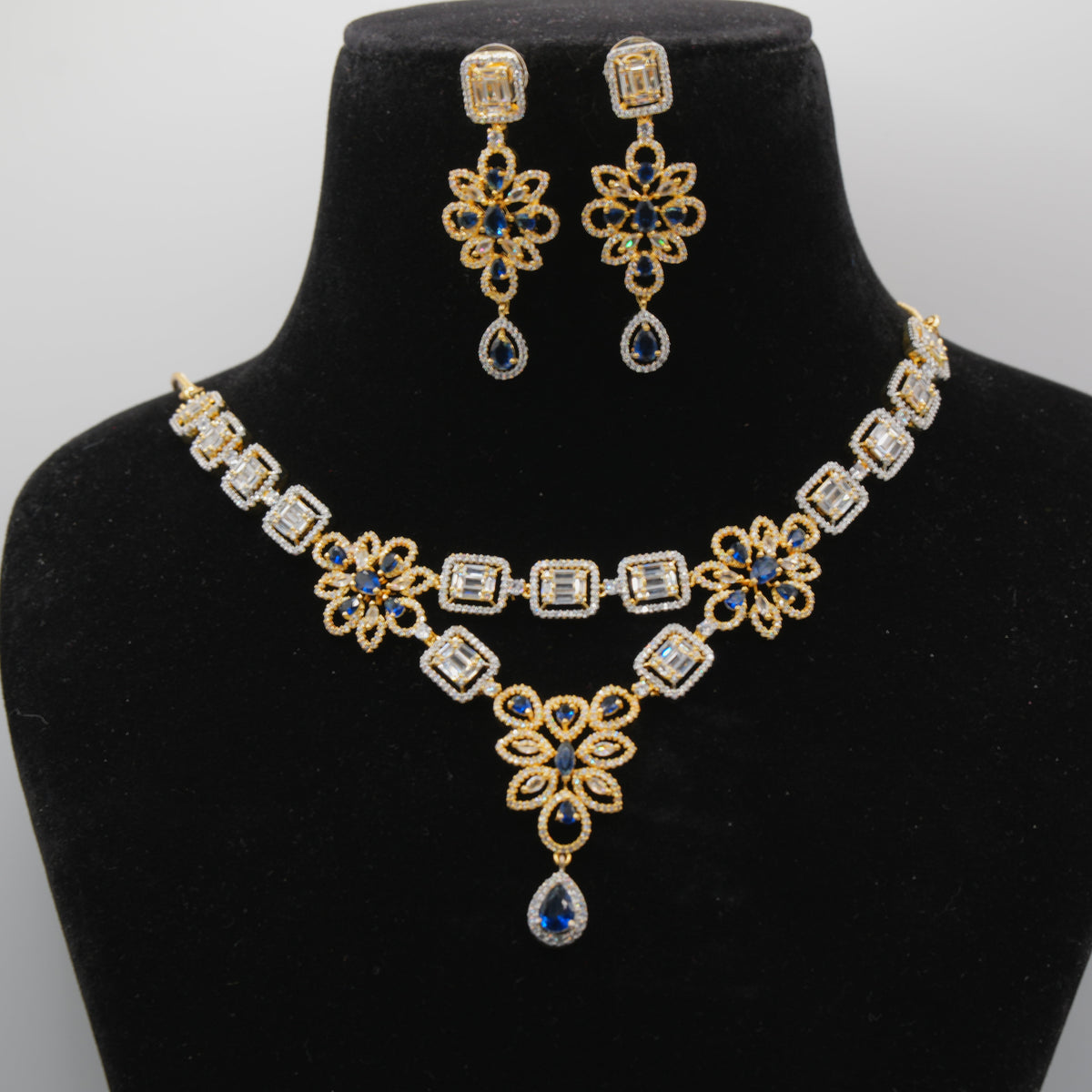 Close up of Royal blue Jewelry set with necklace and earrings on a black mannequin bust against a white background