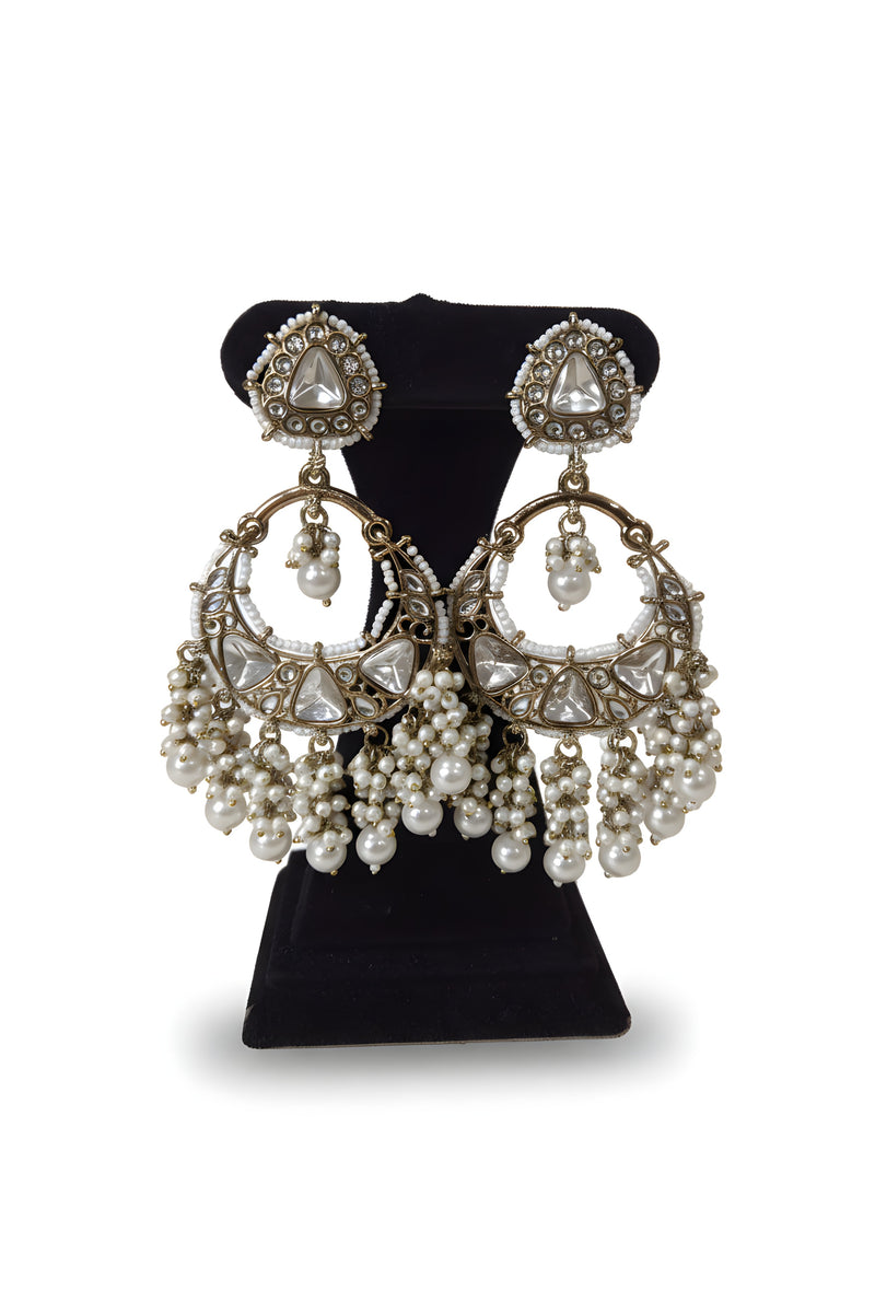 Polki kundan chandbali crescent earrings with triangular polki stones and white baroque pearl cascade on black velvet stand