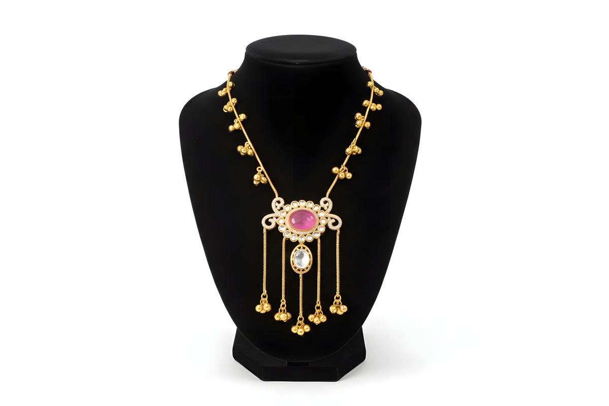 Kashmiri ruby polki long pendant necklace close up showing scrollwork frame ruby cabochon polki drop and gold chain tassels