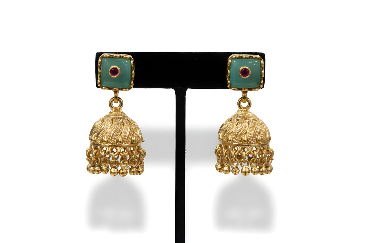Close up gold plated jhumka earrings with mint green stone tops and ruby accents