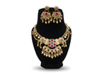 Antique gold plated temple kundan necklace and chandbali earring set with ruby and emerald stones on black display
