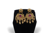 Close up of antique gold chandbali earrings with ruby centre stone and gold leaf drops - Jewellery by Aman