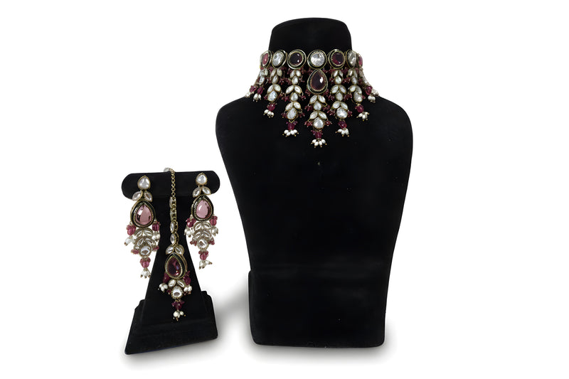Pink polki kundan wedding choker necklace set with long earrings and maang tikka on black display stand