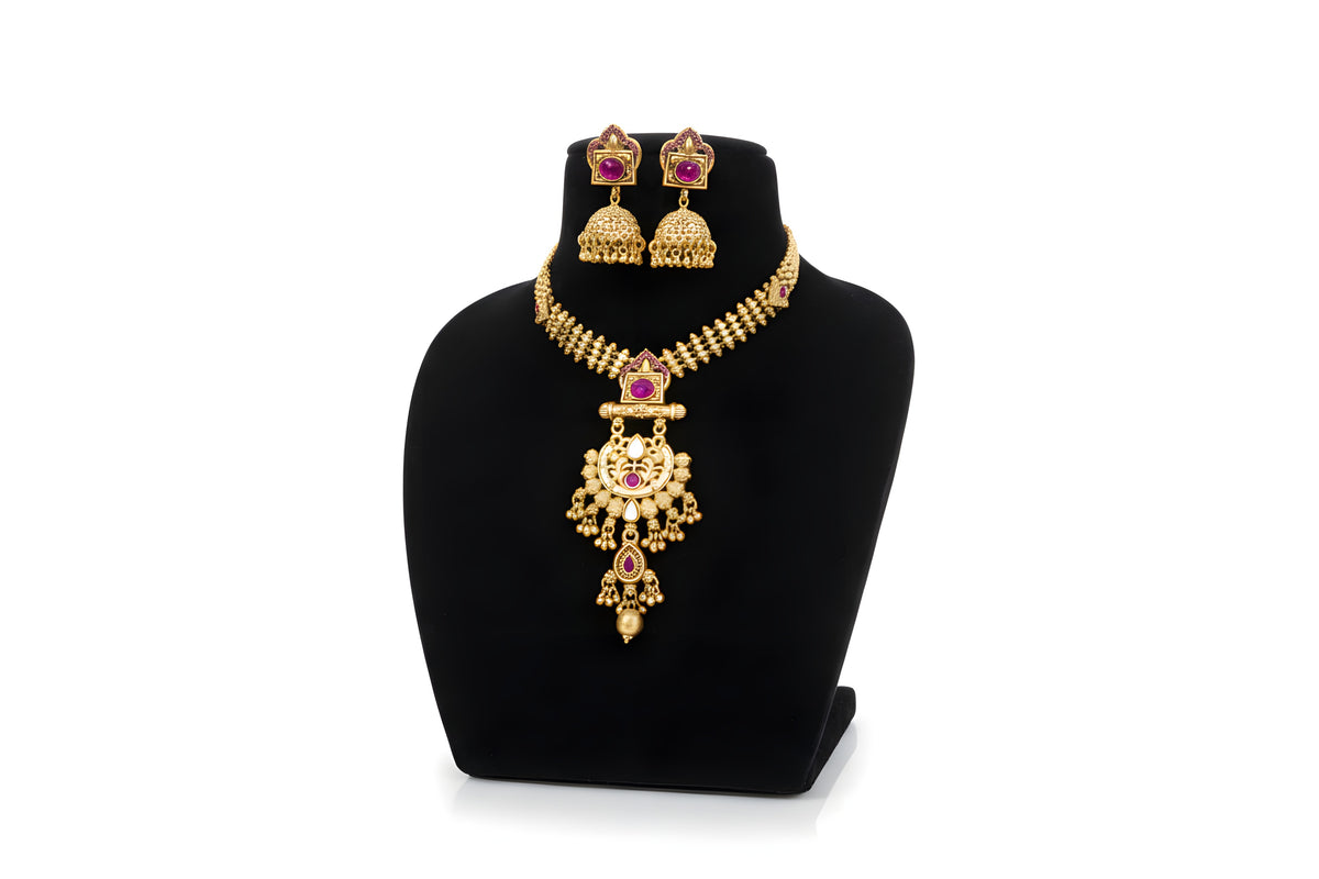 Antique gold pendant necklace set with jhumka earrings - ruby pink stone variant on black display stand