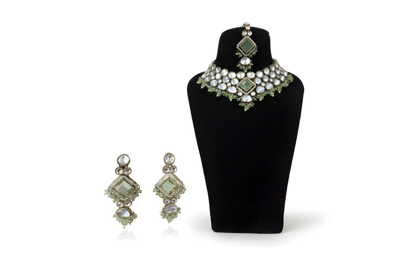 Mint green polki kundan wedding choker necklace set with long earrings and tikka on black display stand