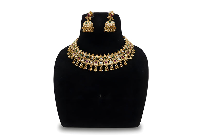 Antique gold temple peacock choker necklace and jhumka earring set with ruby and emerald kundan stones on black display