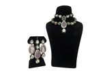 Pink and white polki kundan wedding choker necklace set with long earrings on black display stand