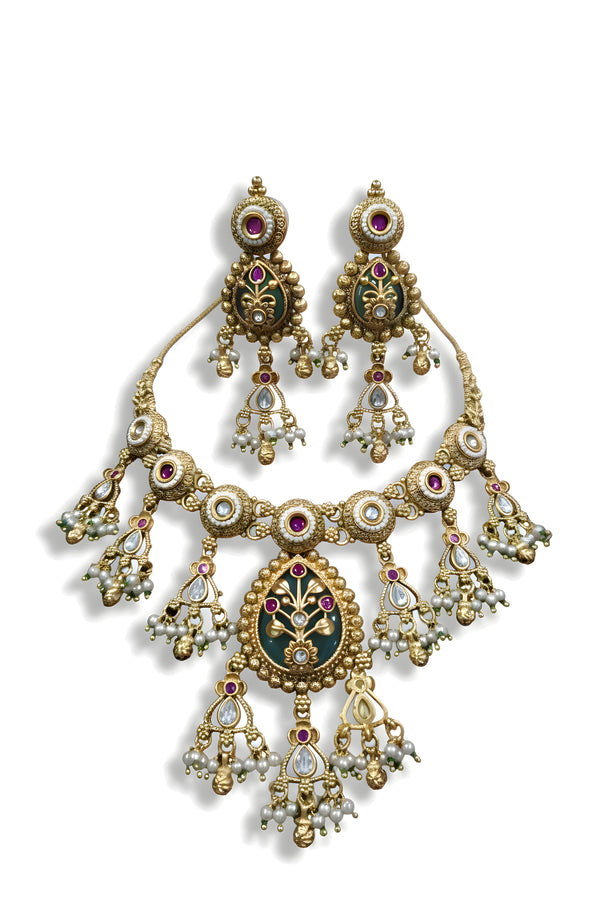 Antique gold meenakari kundan necklace and earring set with ruby and pearl drops on black display stand