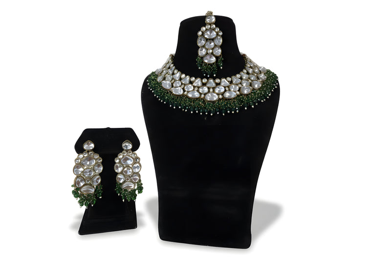 Polki kundan wedding choker necklace set with large earrings tikka and emerald green bead fringe on black display stand