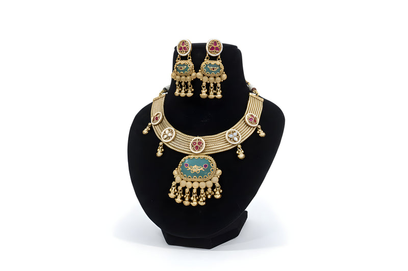 Antique gold green meenakari choker necklace and earring set with ruby stones and temple bell drops on black display