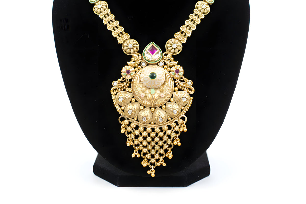 Close up of antique gold ornate pendant necklace with emerald centre ruby teardrop and cascading ghungroo ball drops