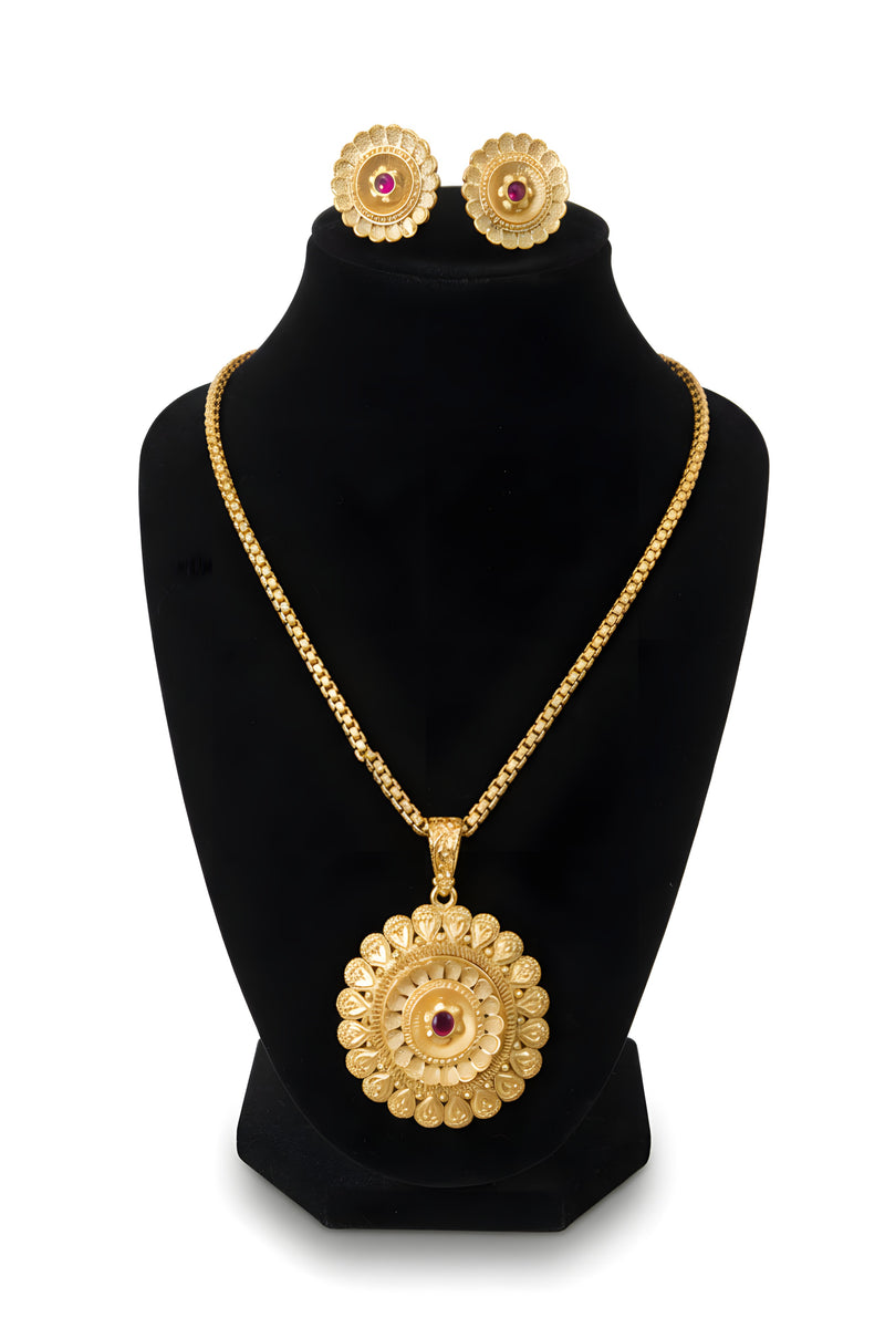 Gold plated circular medallion pendant necklace and matching ruby centre stud earrings displayed on black velvet bust
