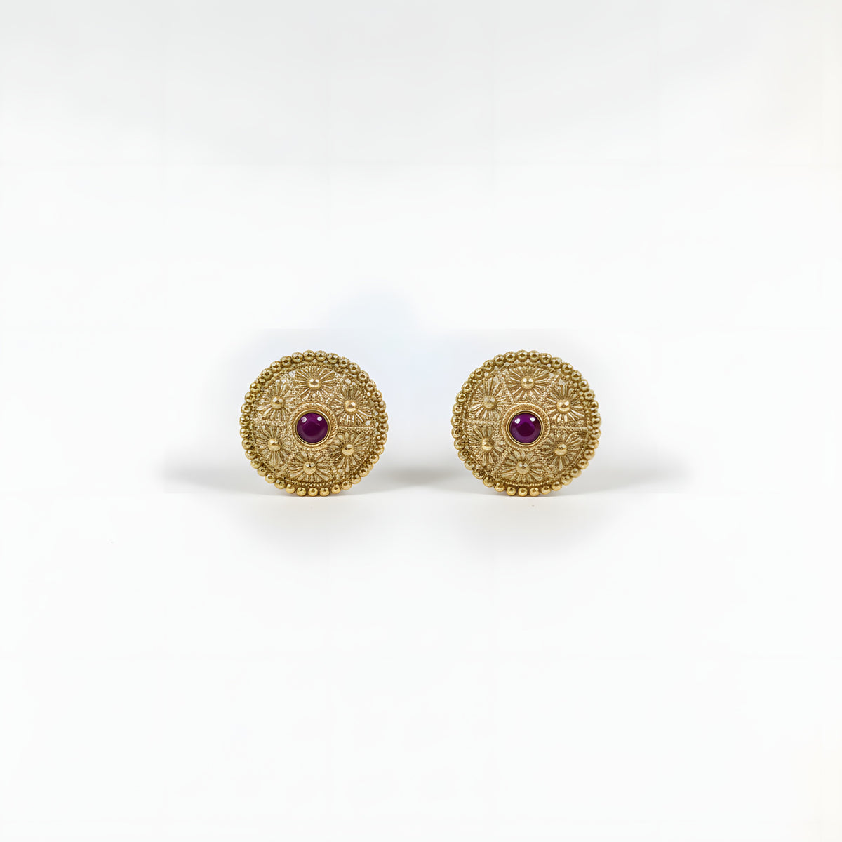 Close up of gold plated circular floral filigree stud earrings with ruby red centre stone and beaded border
